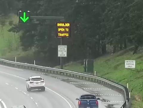 Image of open-part time shoulder with electronic signs and emergency pullout area.