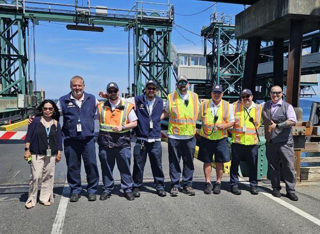 A group of eight people wearing uniforms and safety gear stand at Anacortes terminal.